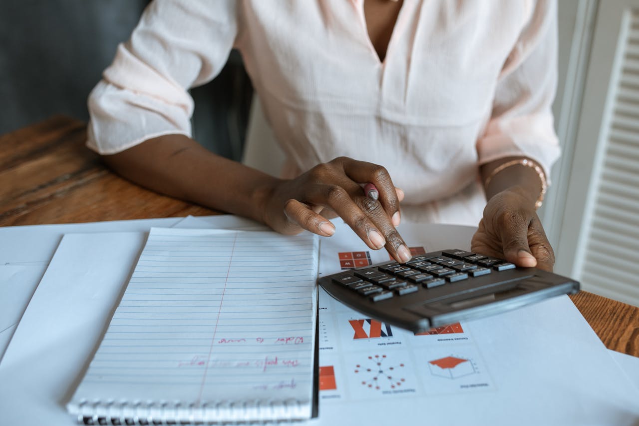 our-services-3 A professional woman calculating finances at a desk with charts and a calculator.